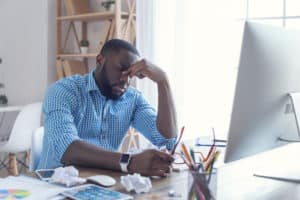 Image of a man sitting my a computer looking tired