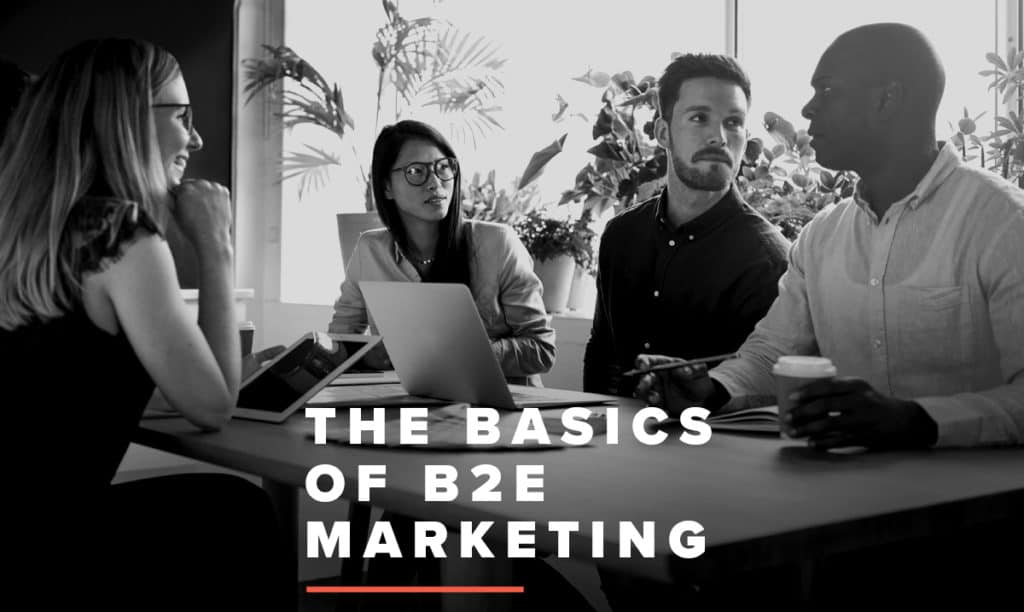 Picture of people sitting around a table talking with a text overlay that reads, "The Basics of B2E Marketing"