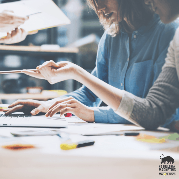 Picture of two women looking at a computer in a business setting. Used for blog about outsourcing work.